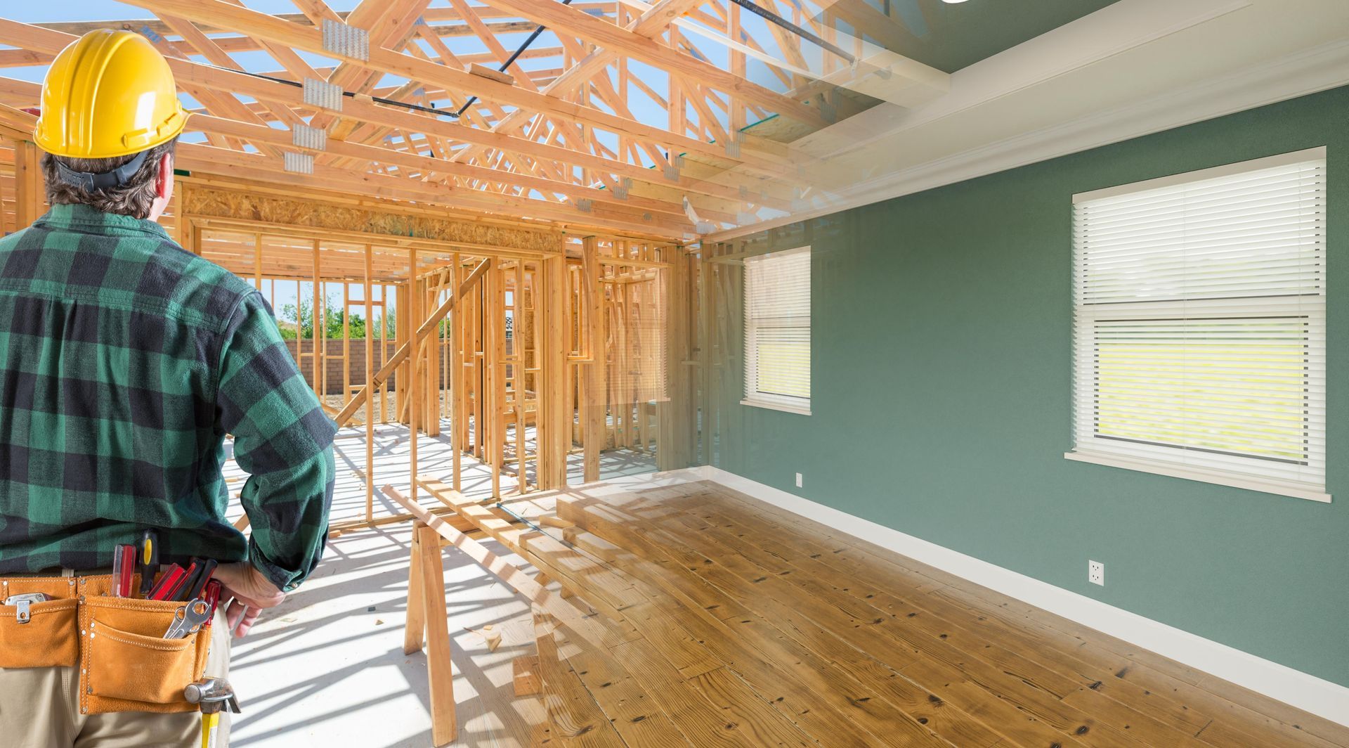 A construction worker is standing in front of a house under construction.