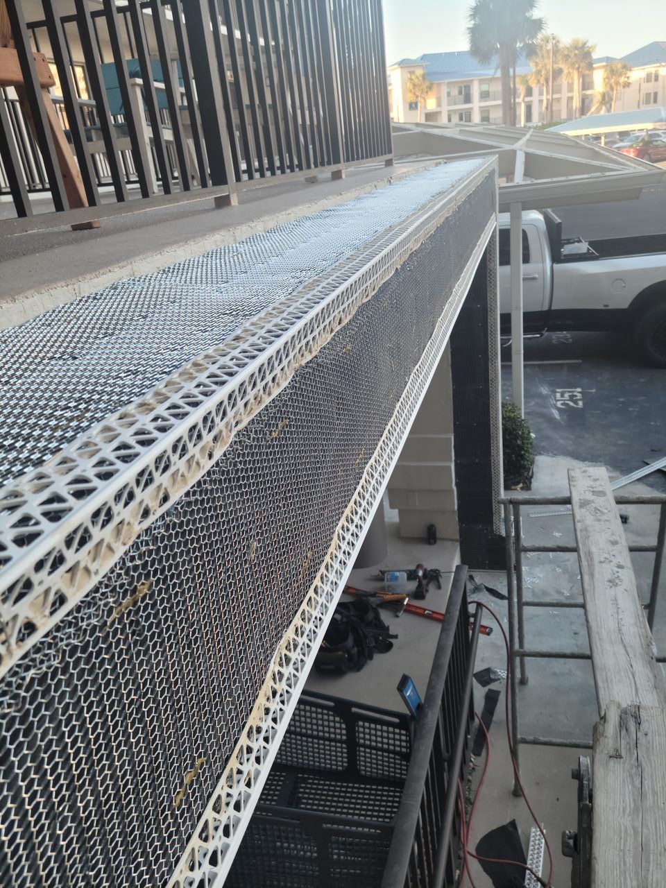 A white truck is parked in a parking lot next to a fence.