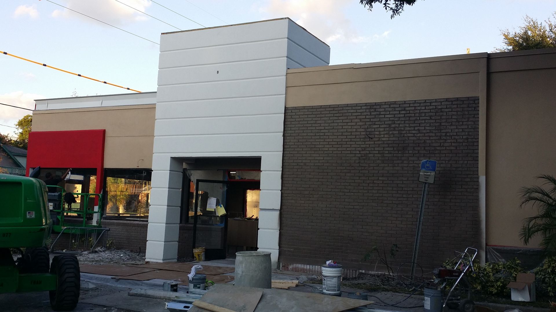 A green tractor is parked in front of a building under construction
