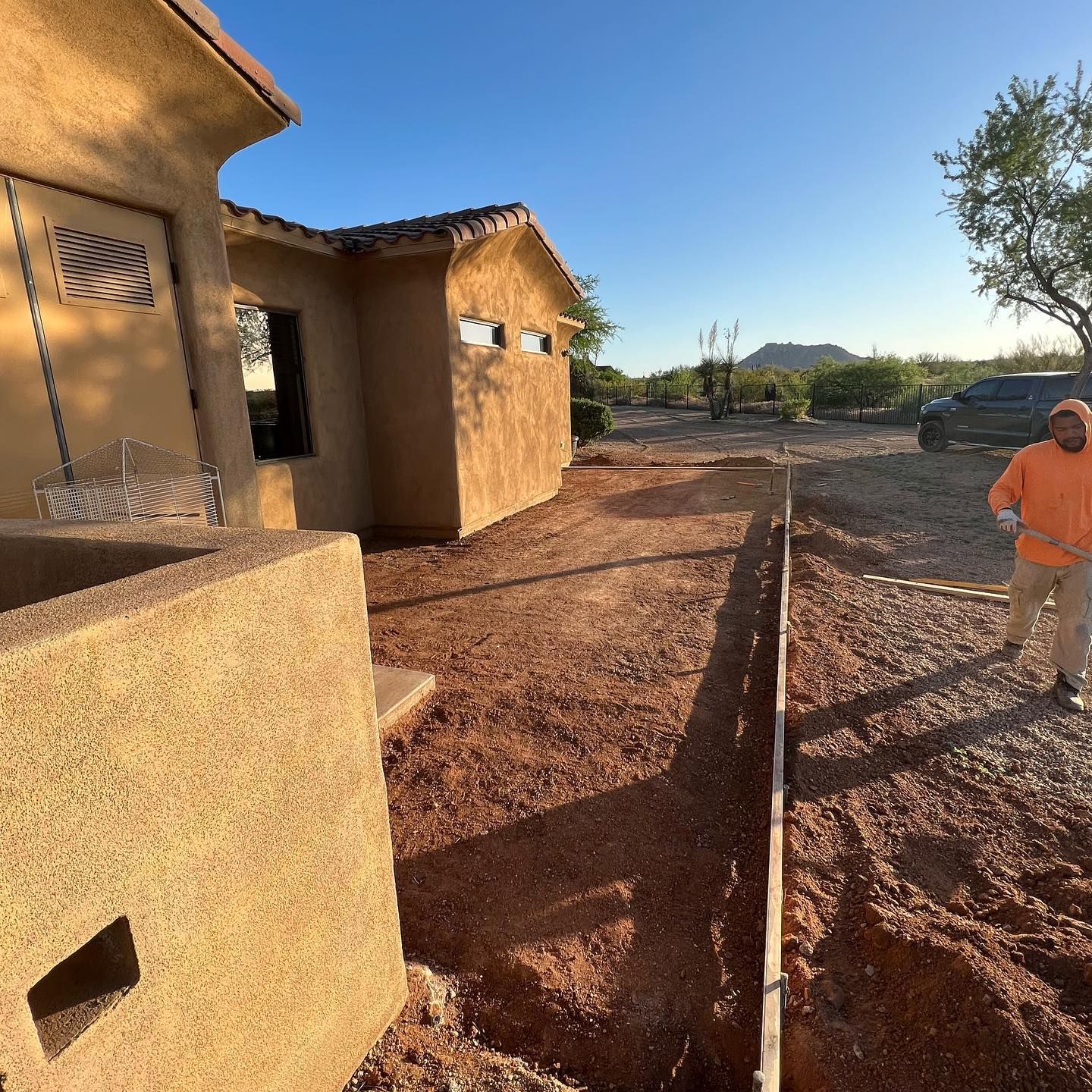 A man is digging in the dirt in front of a house
