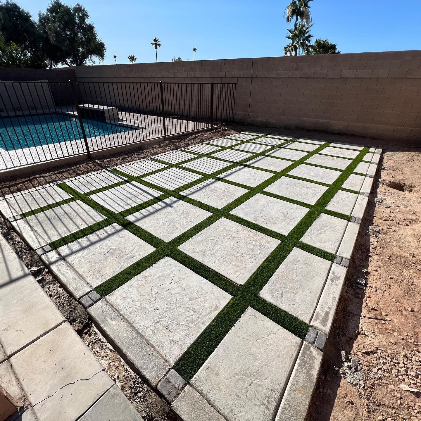 A patio with a fence and a pool in the background