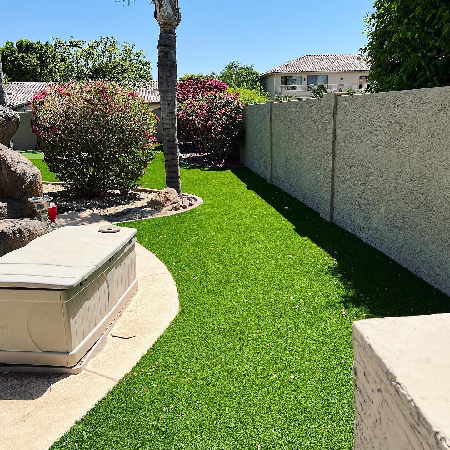 A backyard with a concrete fence and a lush green lawn