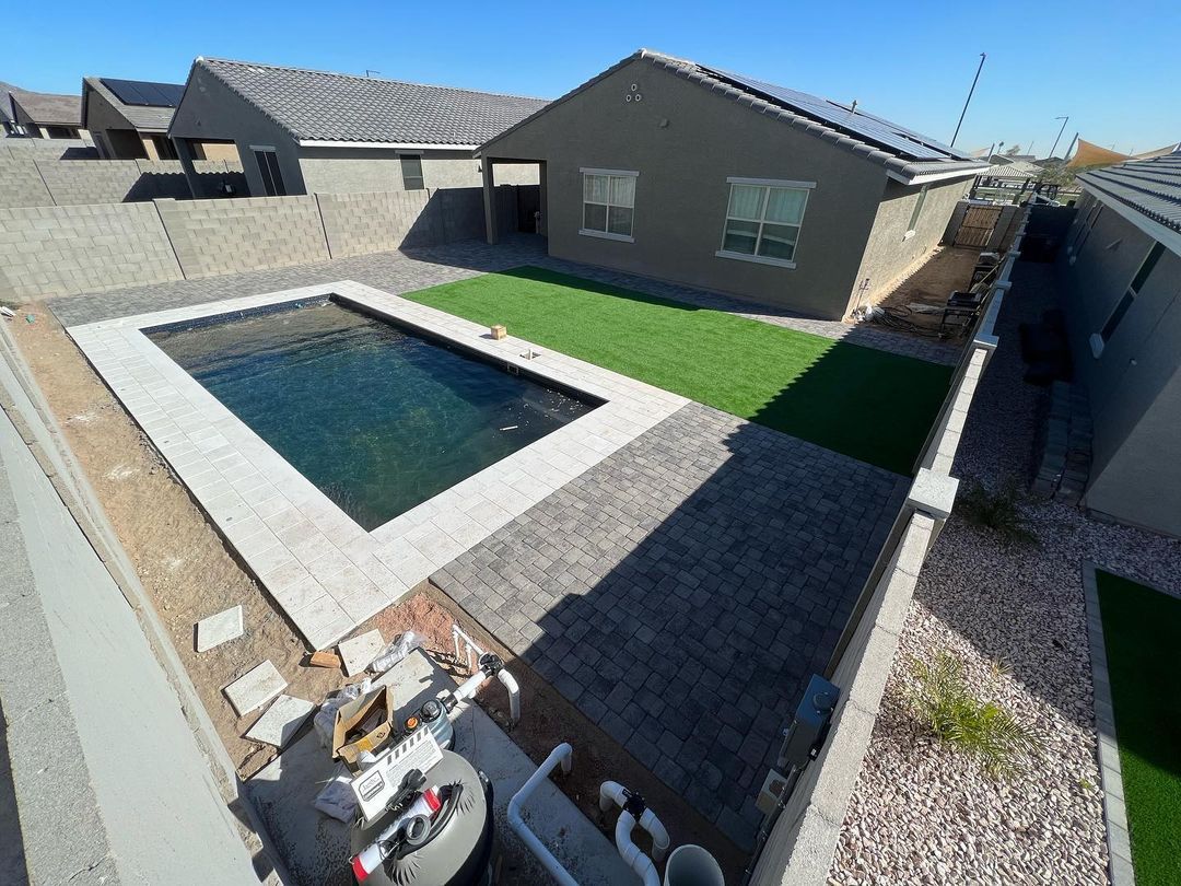 A large swimming pool is in the backyard of a house.