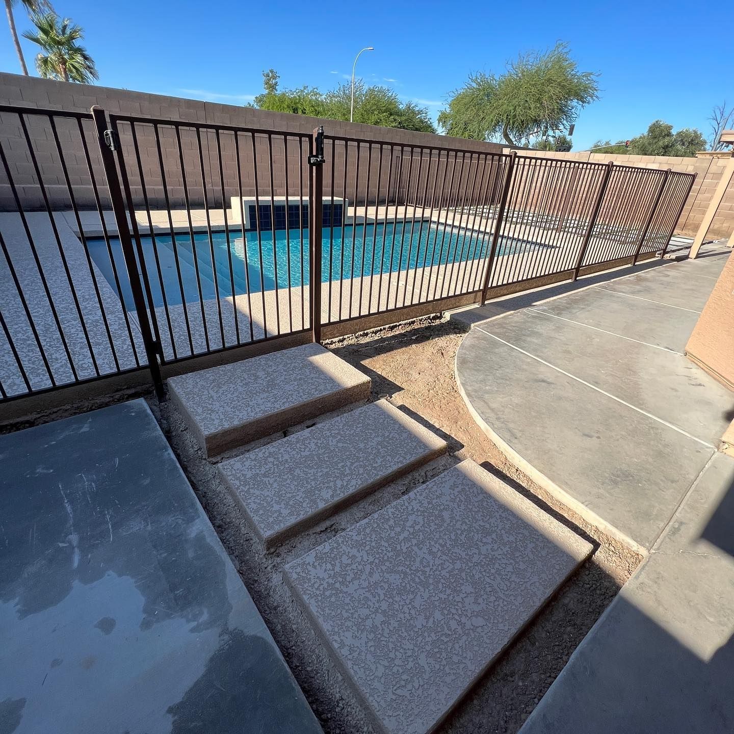 A fence surrounds a swimming pool with steps leading to it
