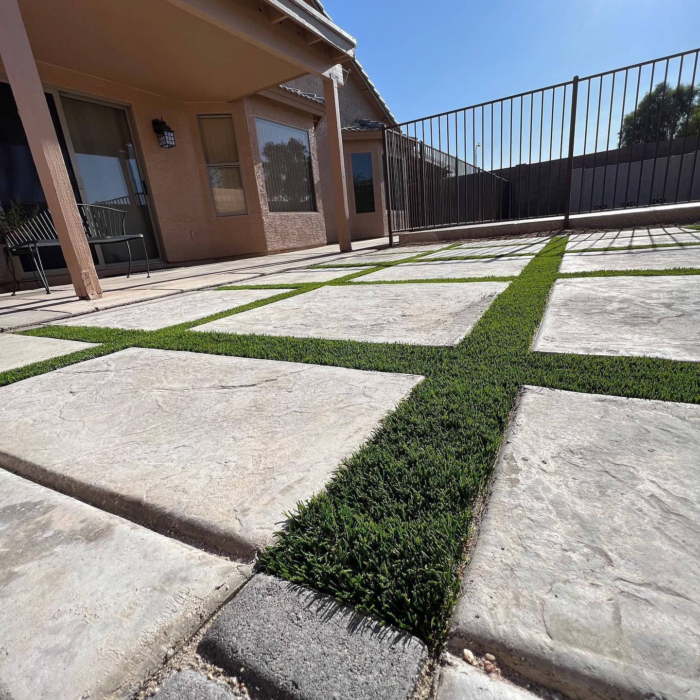 A patio with grass growing between the tiles
