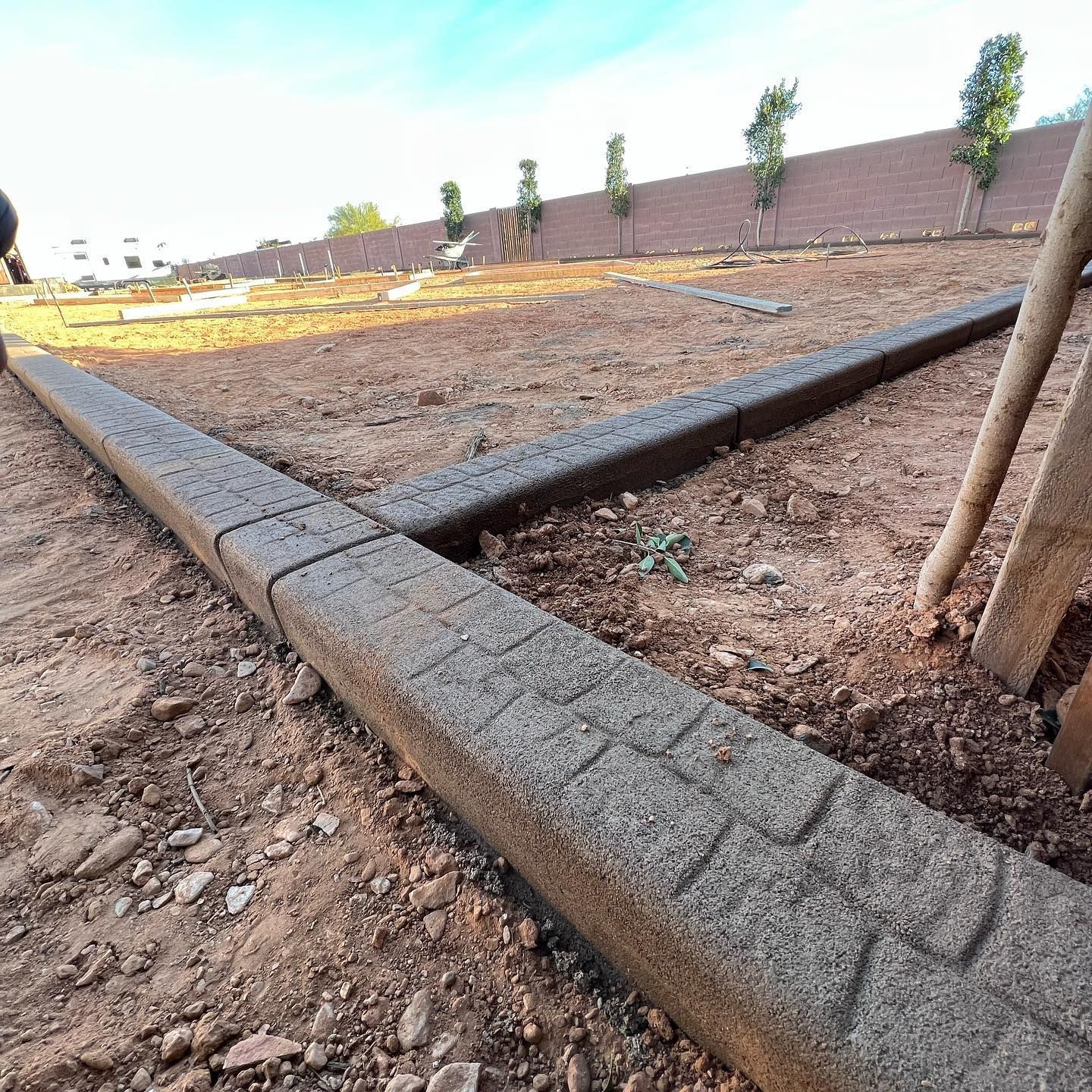 A concrete curb is sitting in the middle of a dirt field.