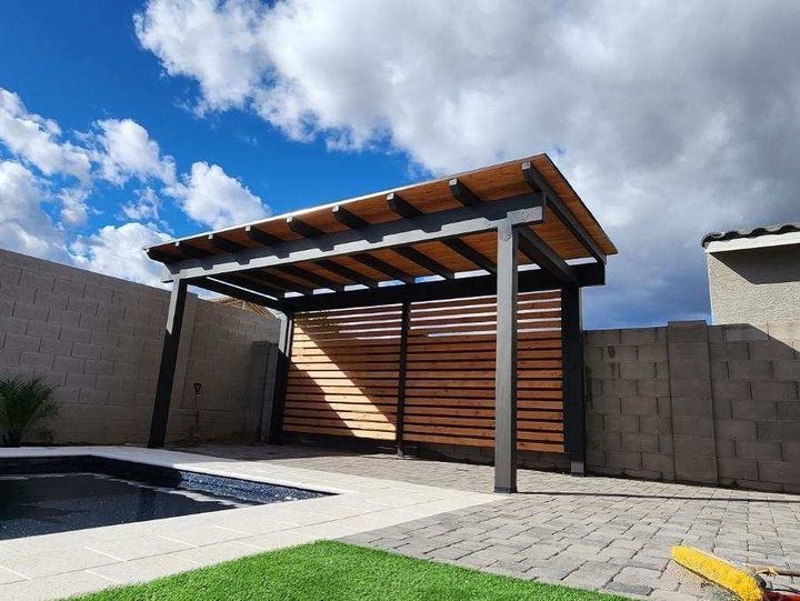 A wooden pergola is sitting next to a pool in a backyard.