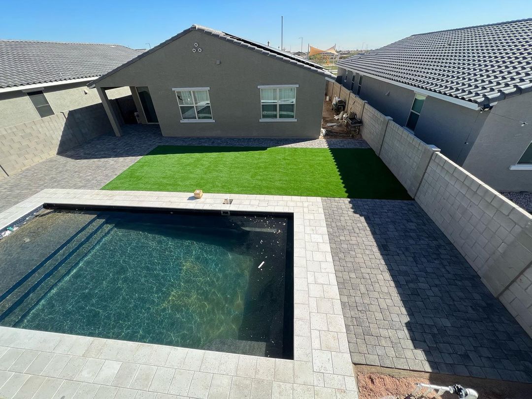 A large swimming pool is in the backyard of a house.