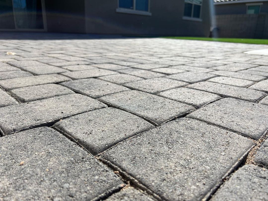 A close up of a brick driveway with a house in the background.