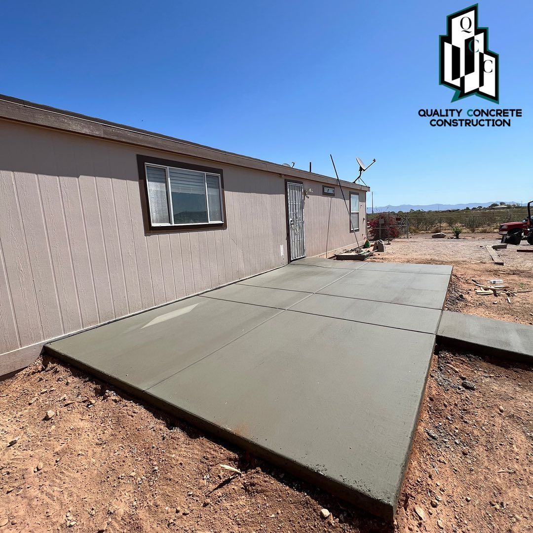 A concrete patio is being built in front of a house by quality concrete construction