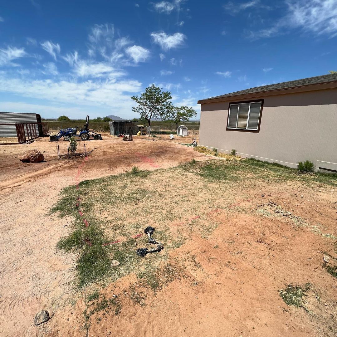 A house is sitting in the middle of a dirt field.