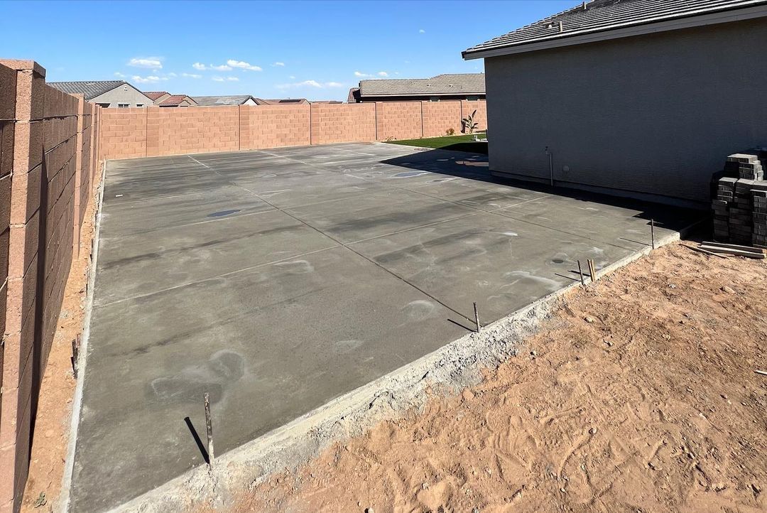 A concrete driveway is being built in the backyard of a house.