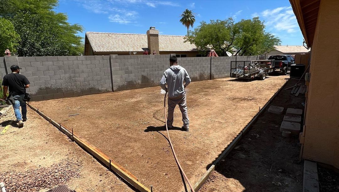 A man is standing in the dirt in front of a house.