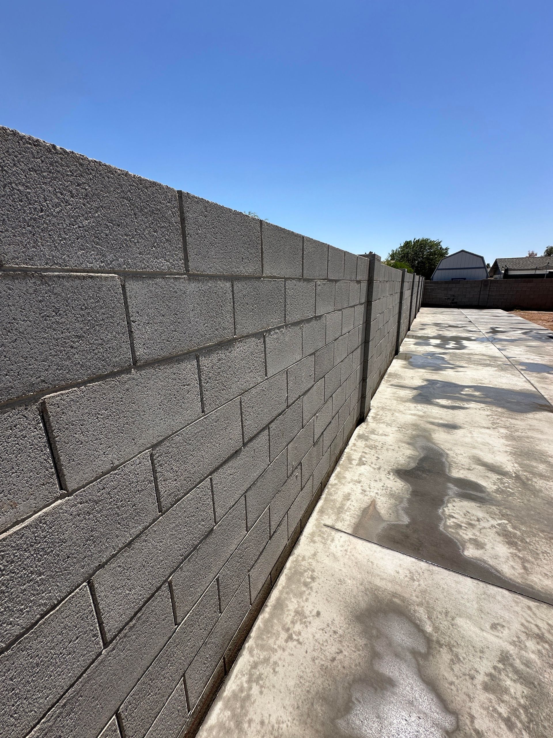 A brick wall along a sidewalk with a blue sky in the background.