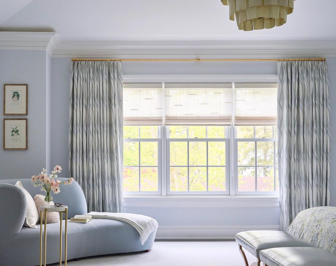 Elegant room with a large window, blue walls, a chaise lounge, patterned curtains, and a chandelier.