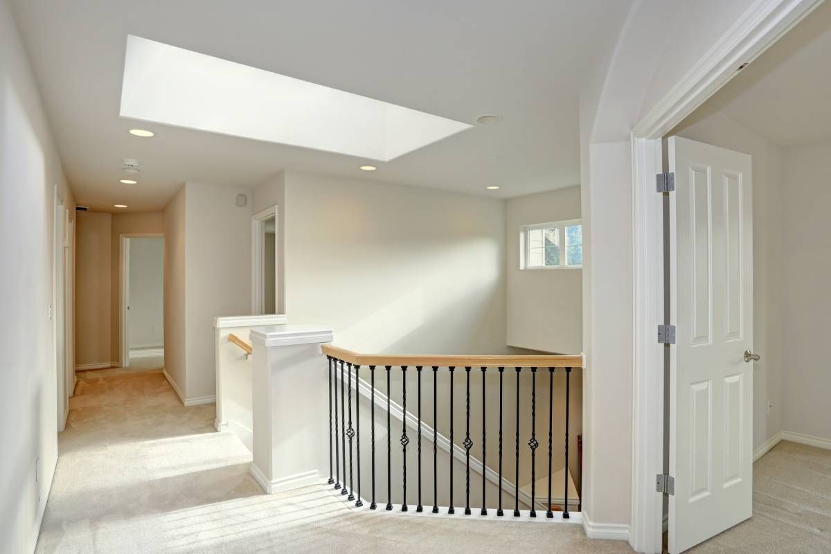 Hallway with skylight, staircase, and open doorway, bathed in natural light.