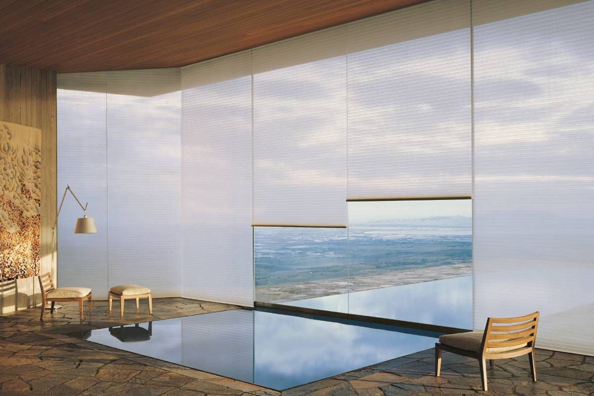 Room with sheer white window coverings, chairs, and a view of water.