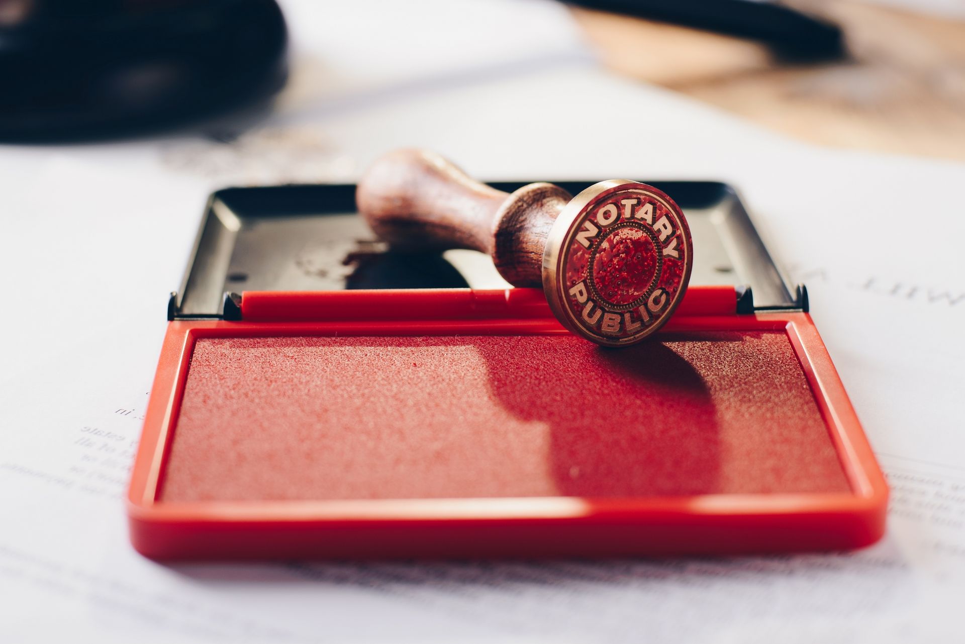 Red notary stamp on a red ink pad, atop a white table.