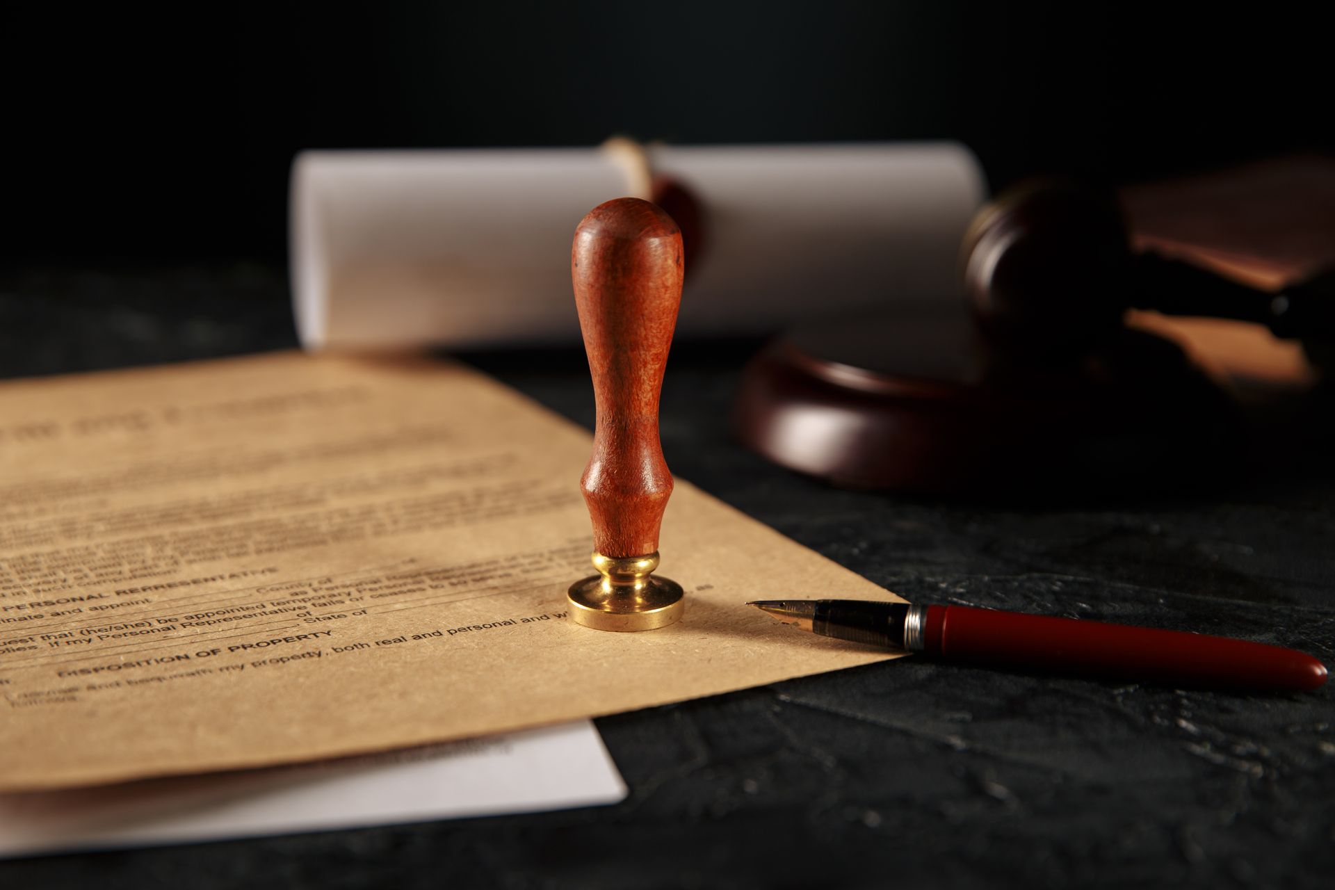 Seal and gavel on a desk with a document, pen, and rolled scroll.
