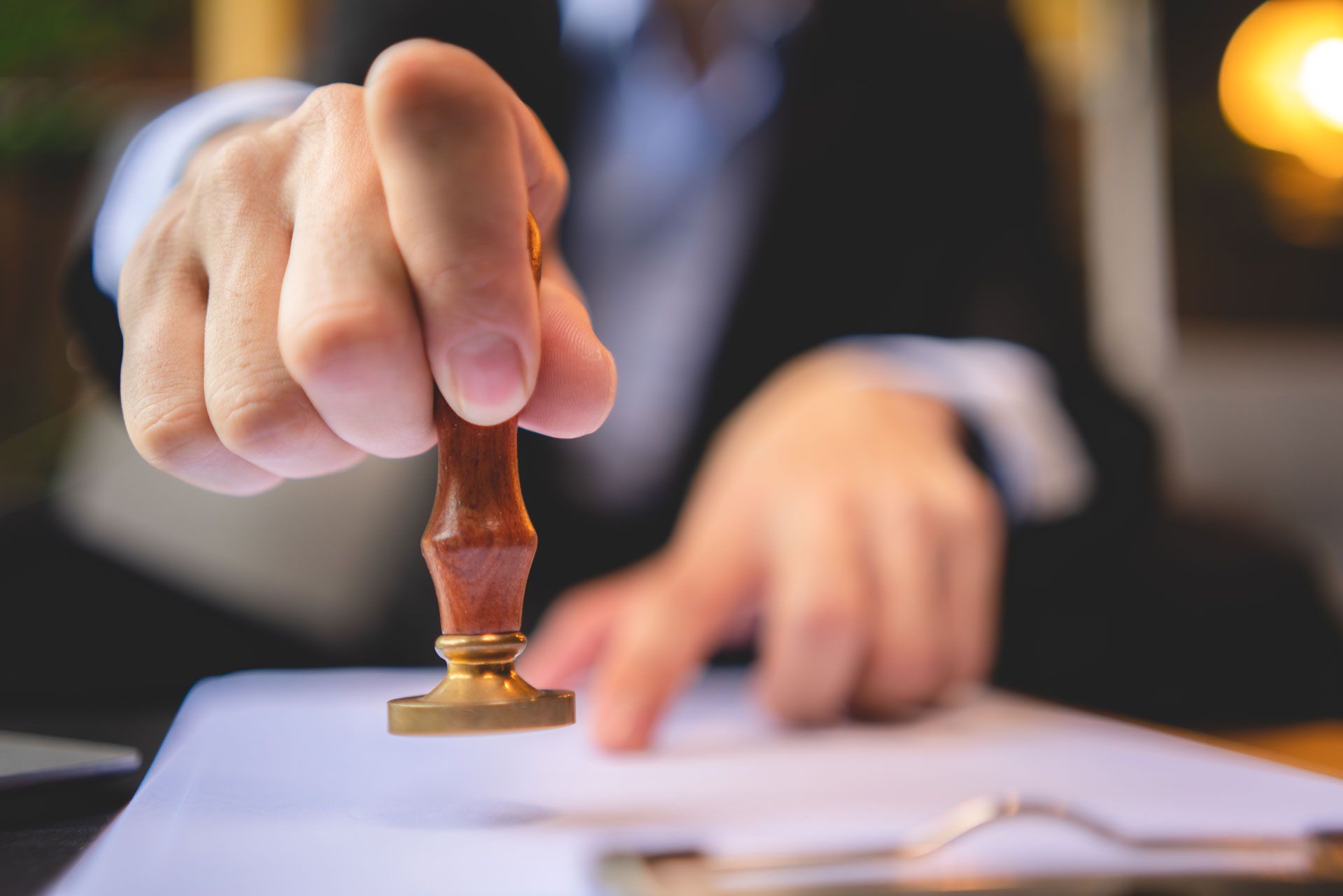 Person in business attire about to stamp a document with a seal.