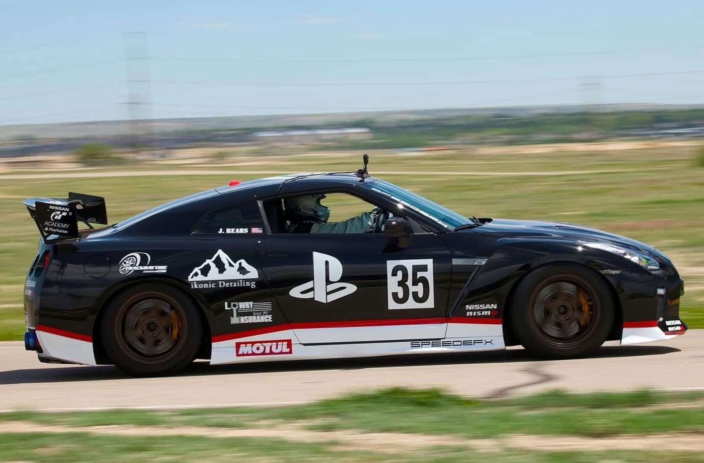 A black race car with the number 35 on the side is driving down a road.