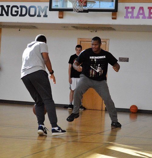 Two men are playing basketball in front of a sign that says ngdom
