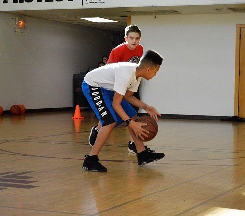 Two boys are playing basketball on a court and one has the word hope on his shorts