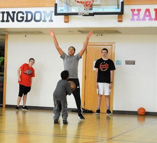 People playing basketball in front of a sign that says ingdom hall