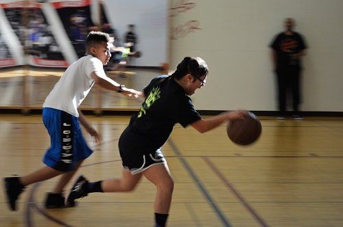 A boy and a girl are playing basketball on a court