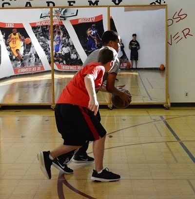 A boy in a red shirt is dribbling a basketball