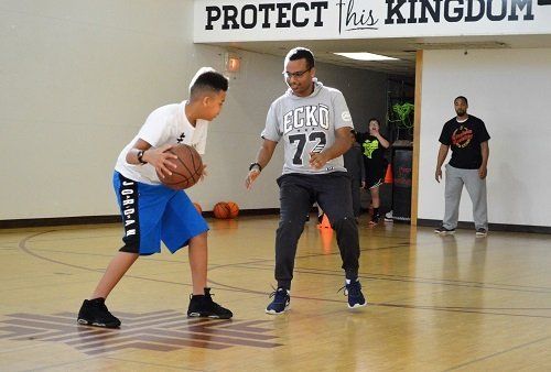 A man and a boy are playing basketball on a court.
