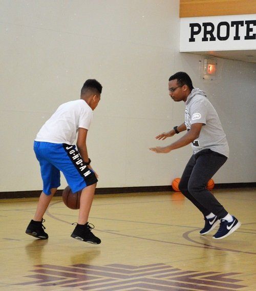 Two men playing basketball in front of a sign that says prote