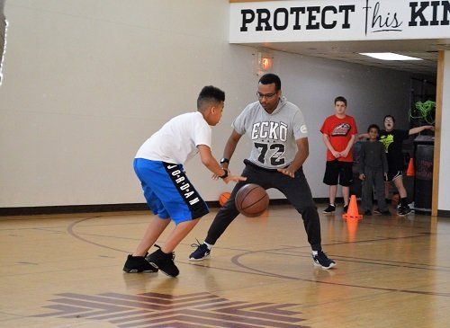 A man and a boy are playing basketball on a court.