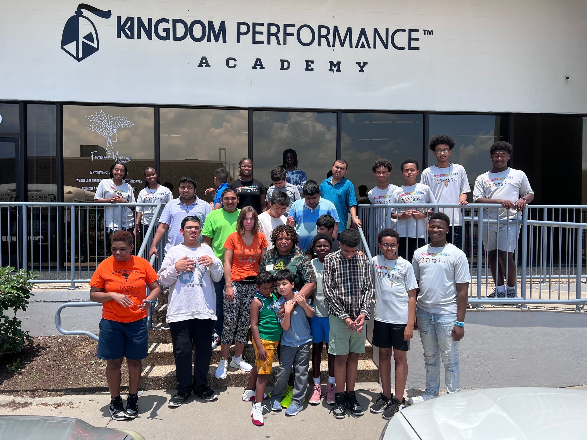A group of people standing in front of a building that says kingdom performance academy