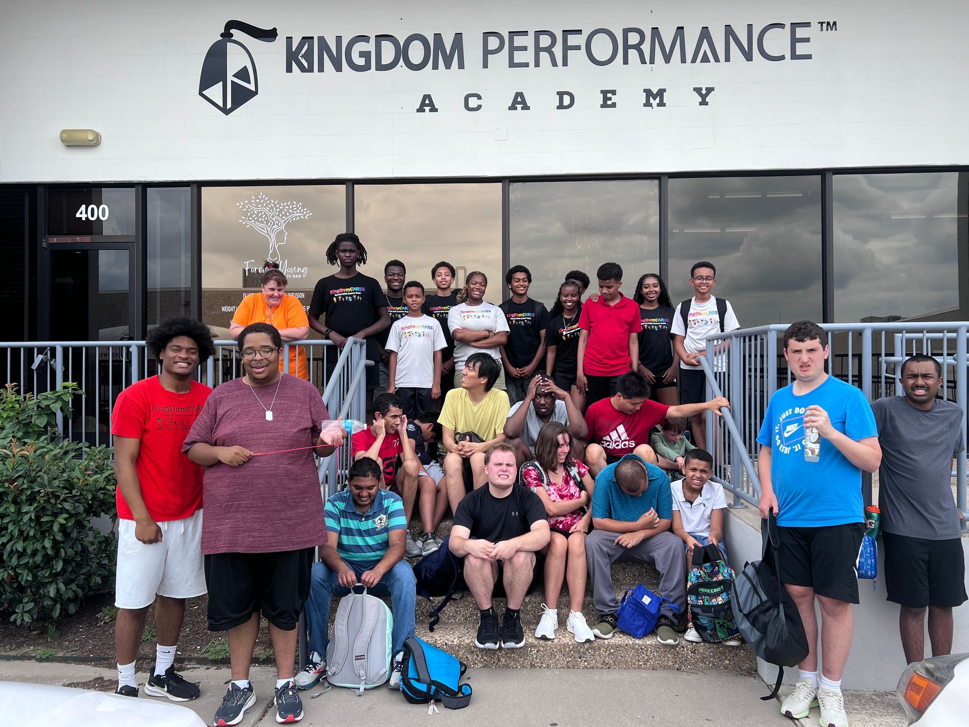 A group of people standing in front of a building that says kingdom performance academy