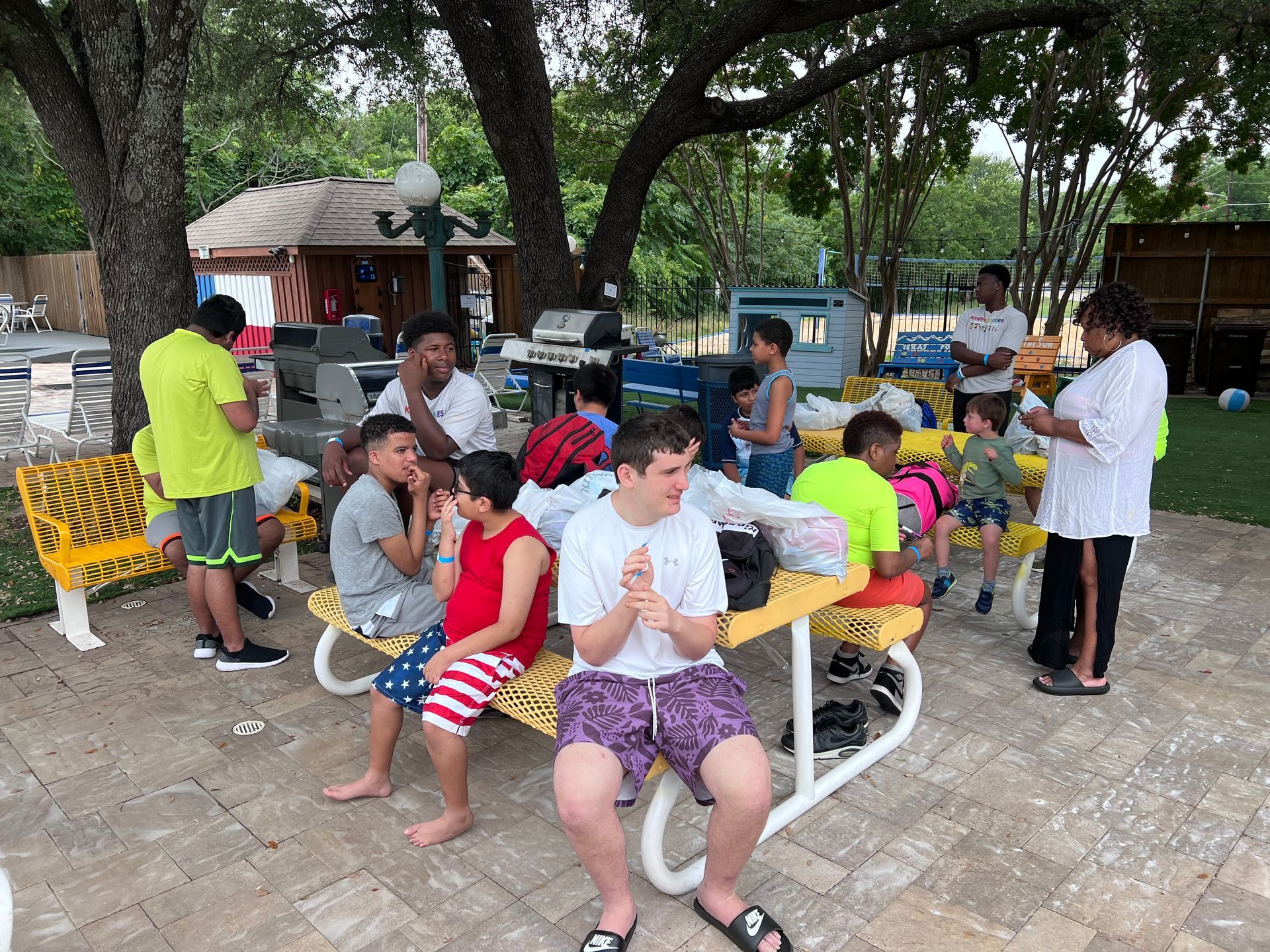 A group of children are sitting at a picnic table eating ice cream.