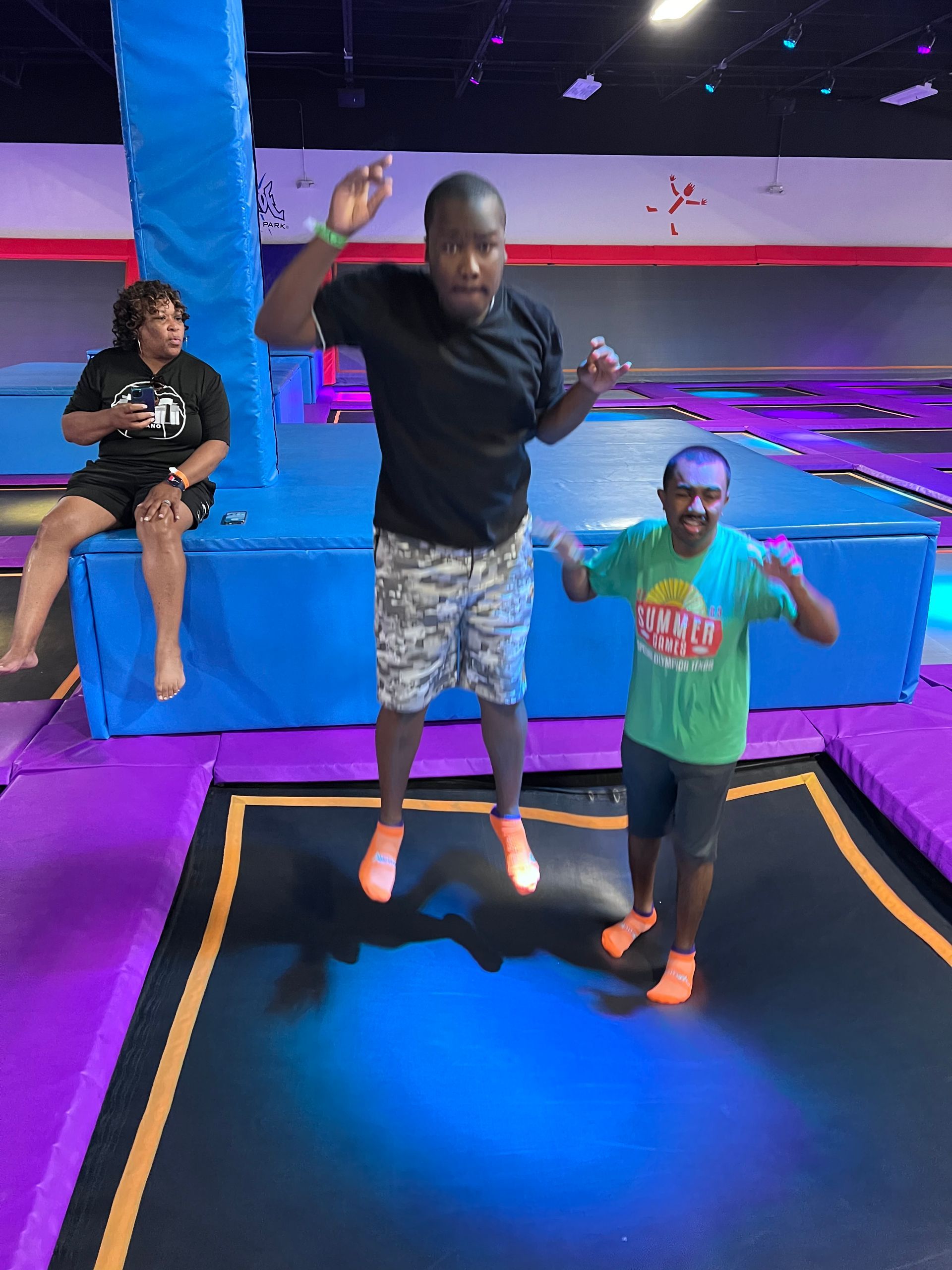 A man and a boy are jumping on a trampoline.