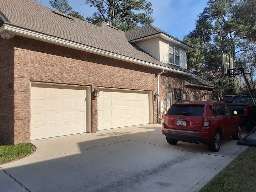 A red jeep is parked in front of a brick house