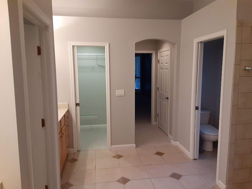 A hallway leading to a bathroom and a toilet in a house.