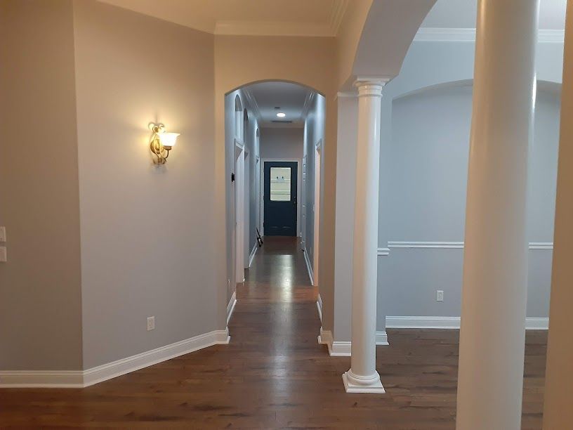 A long hallway in a house with hardwood floors and columns.