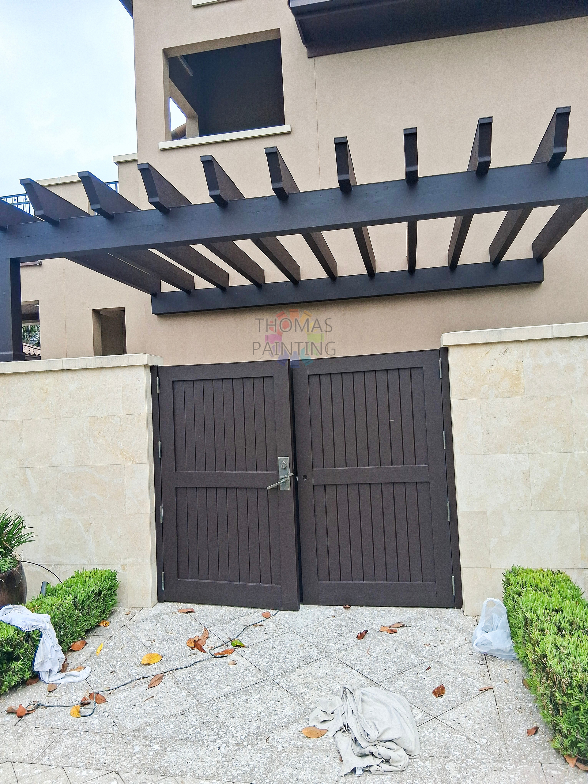 Modern house entrance with dark double gate, white walls, and a black pergola over the driveway