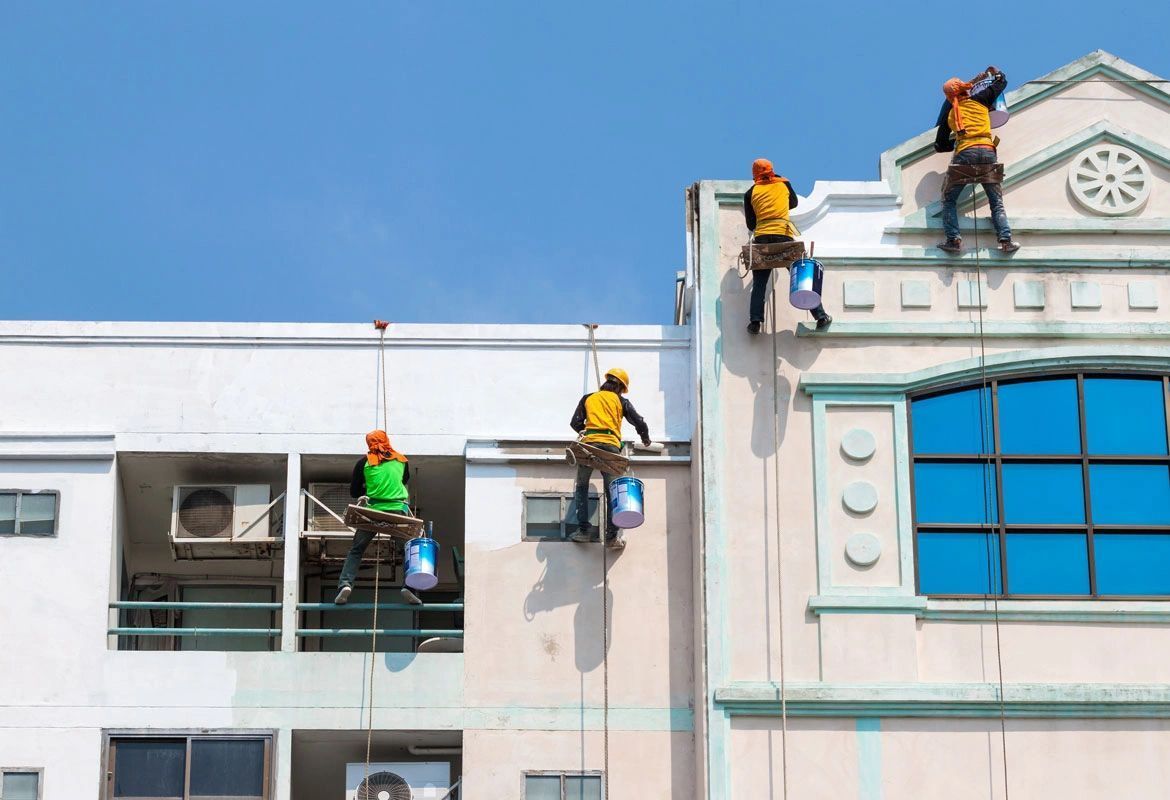 A group of men are painting the side of a building.