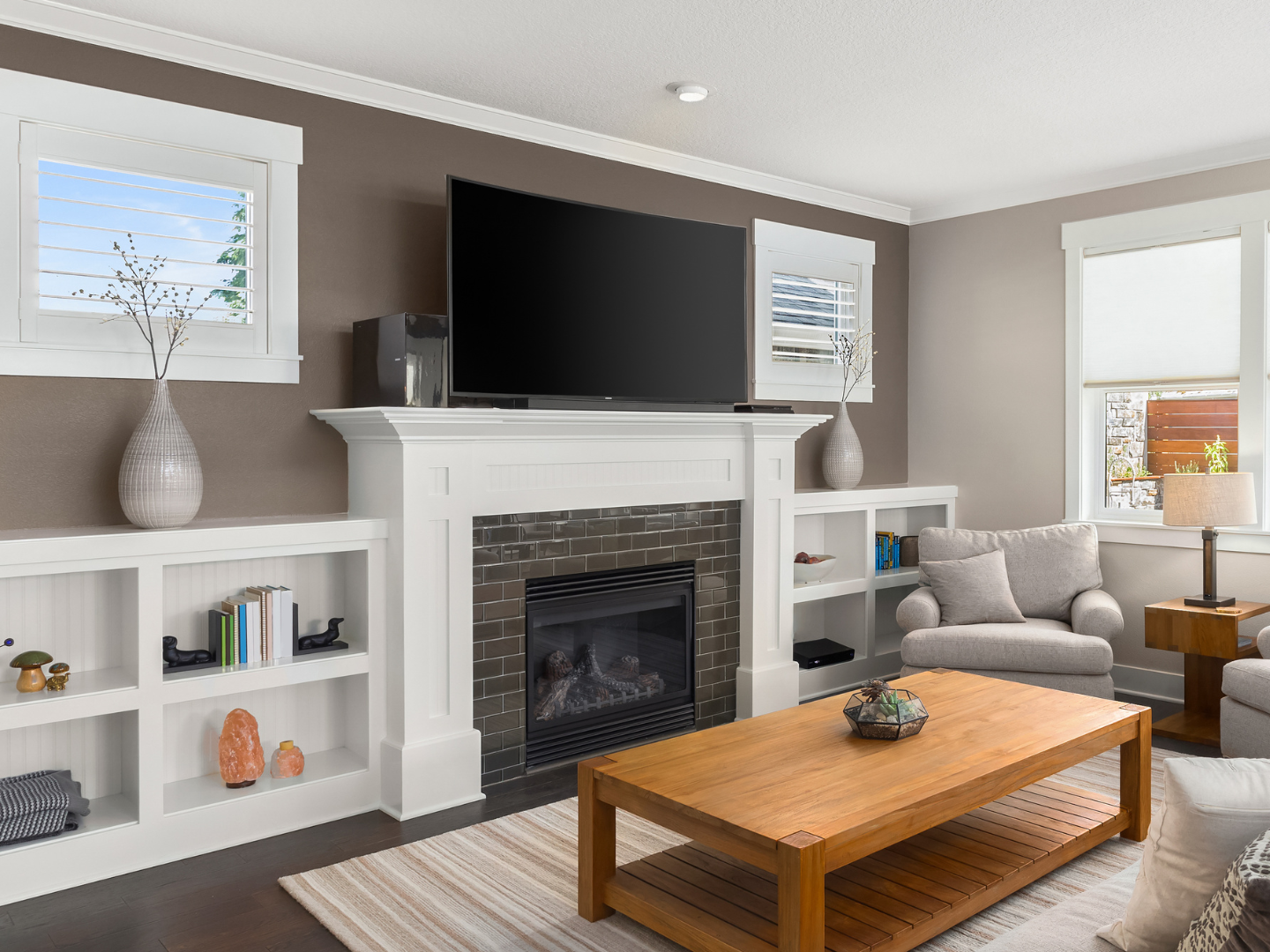 A living room with a fireplace , television , coffee table and chairs.