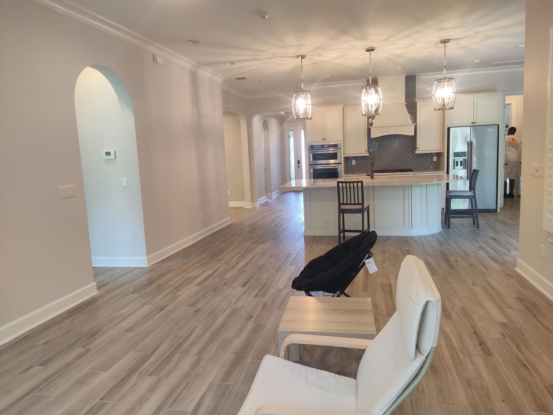 A living room with hardwood floors , a chair , a table and a piano.