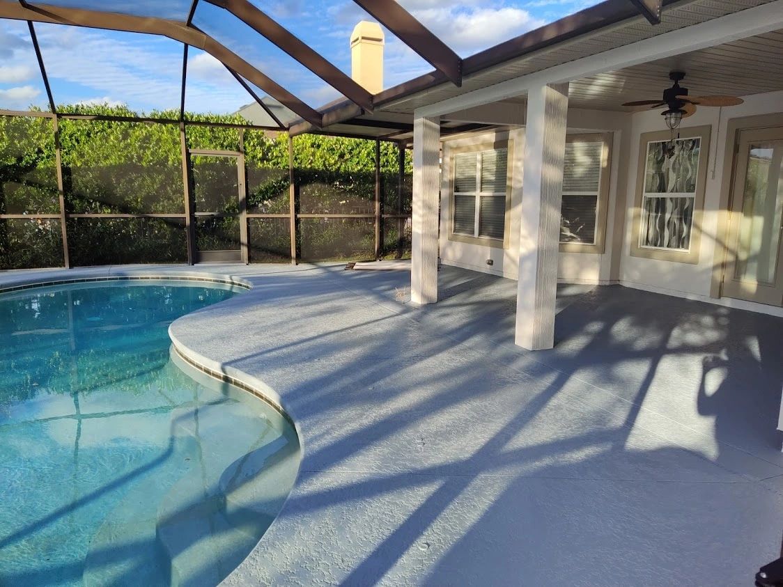 A large swimming pool is surrounded by a screened in porch.