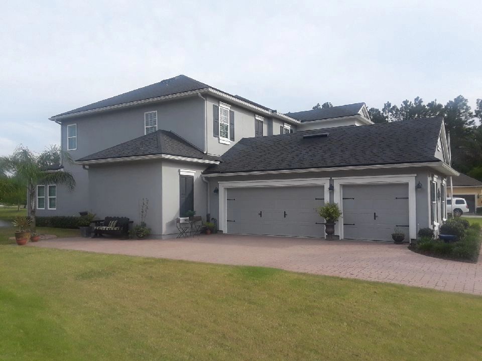 A large house with three garage doors and a brick driveway