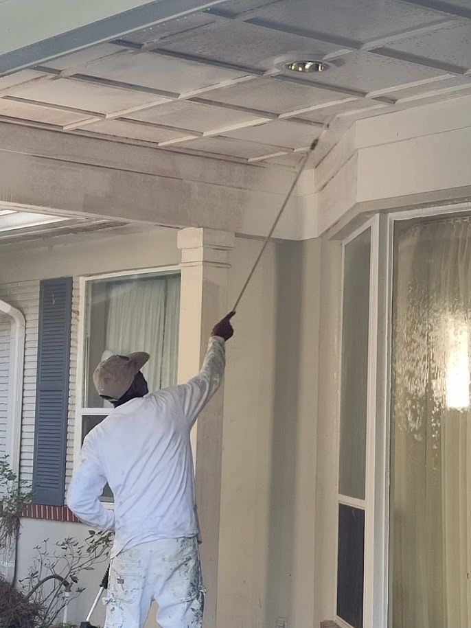 A man is painting the ceiling of a house with a sprayer.