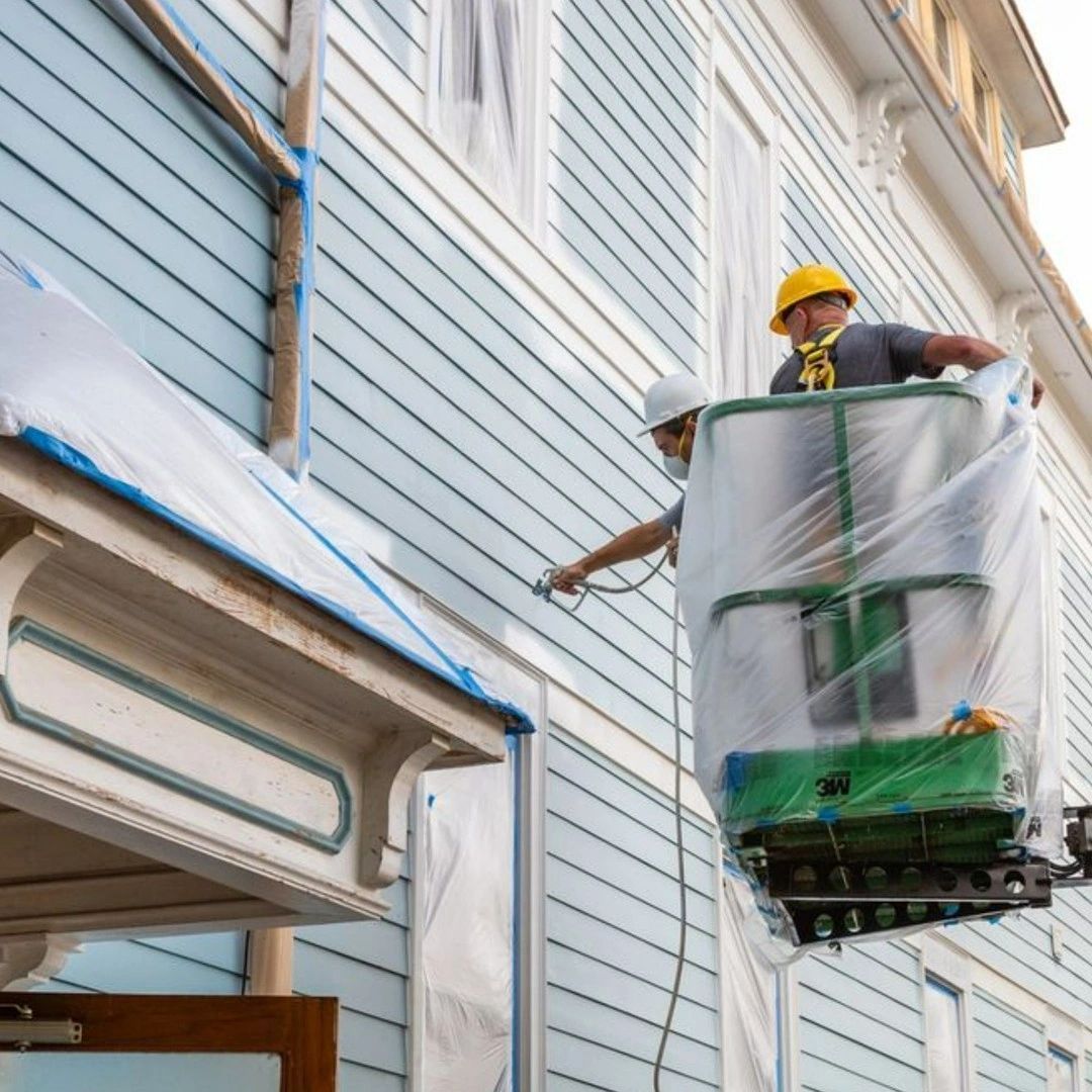 Two men are painting the side of a building
