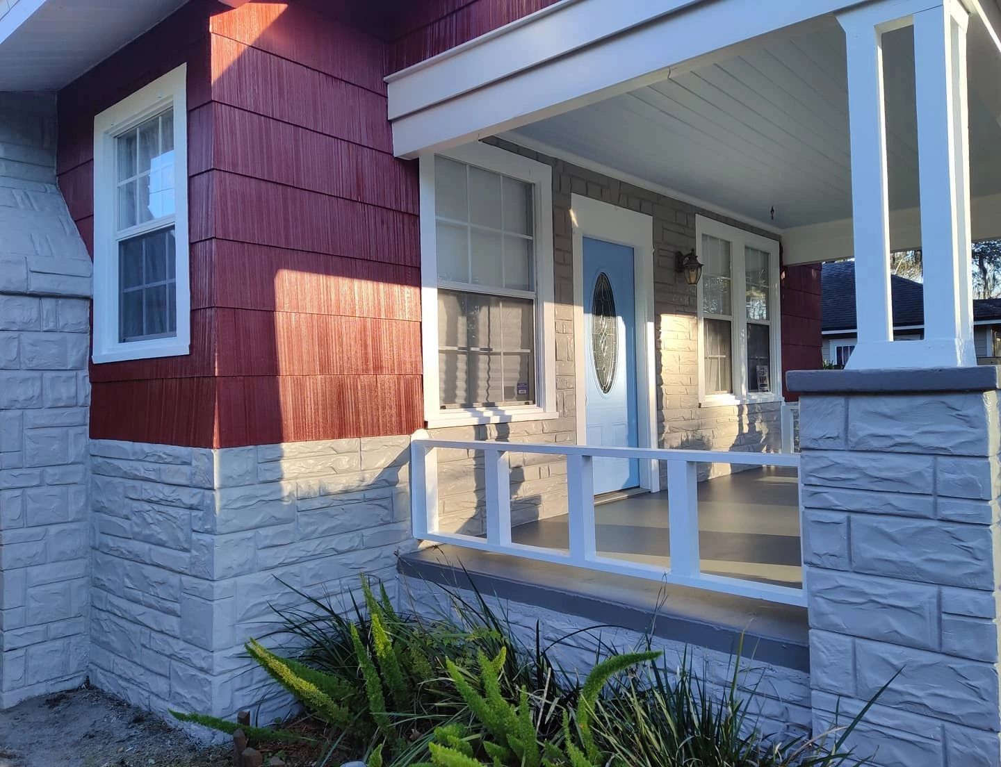 A red and white house with a porch and a white railing