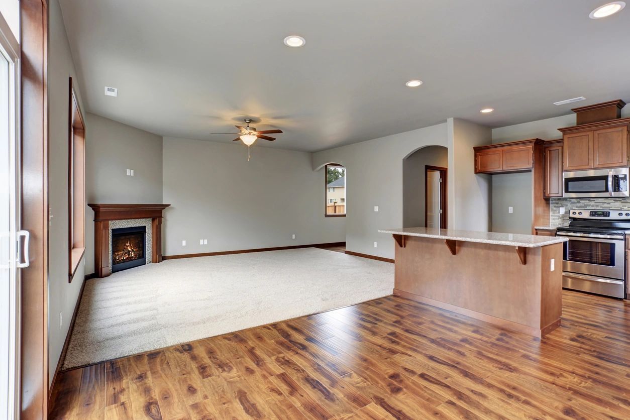 An empty living room with hardwood floors and a fireplace.